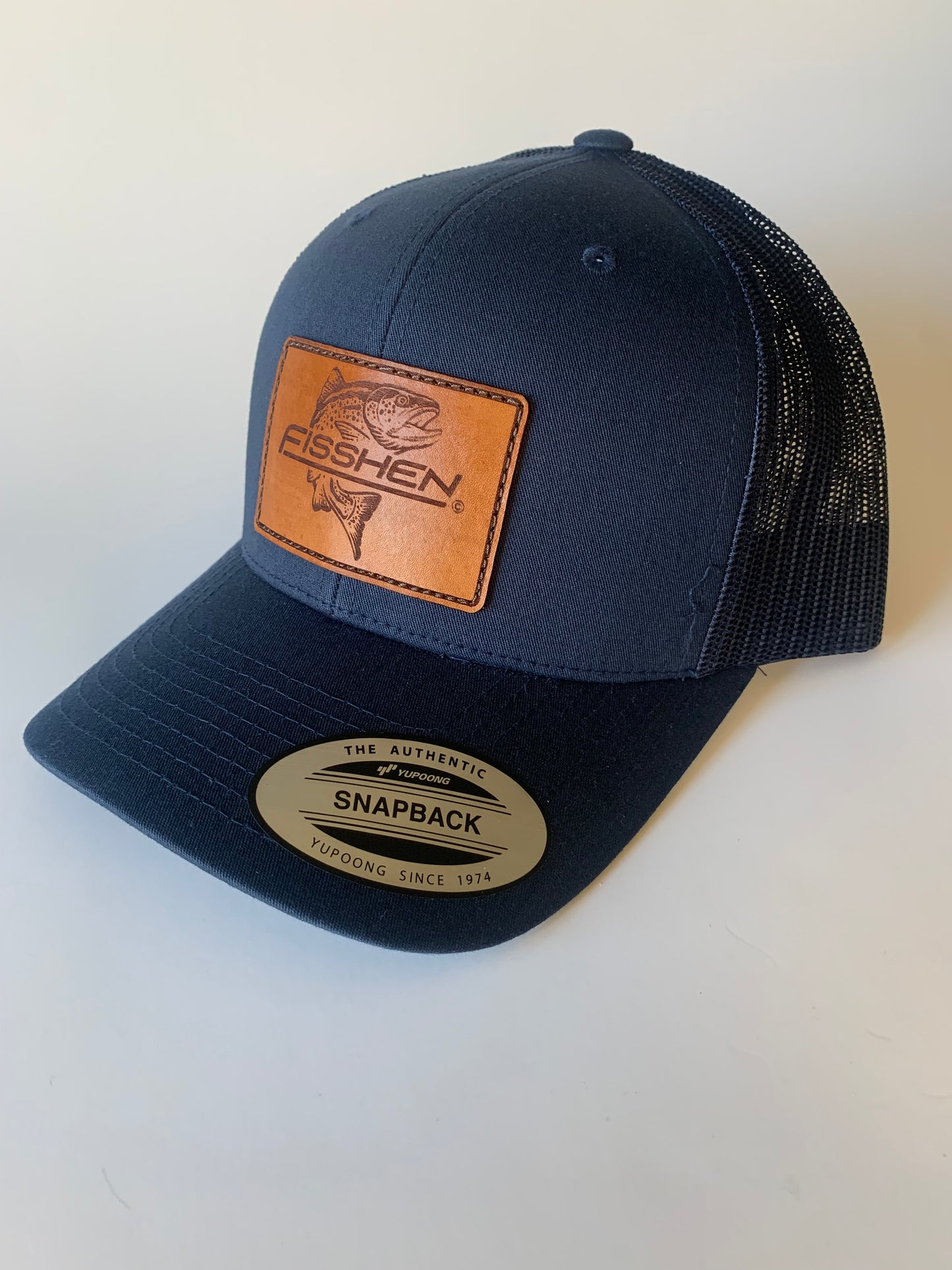 trout logo honey brown leather patch on a navy trucker hat
