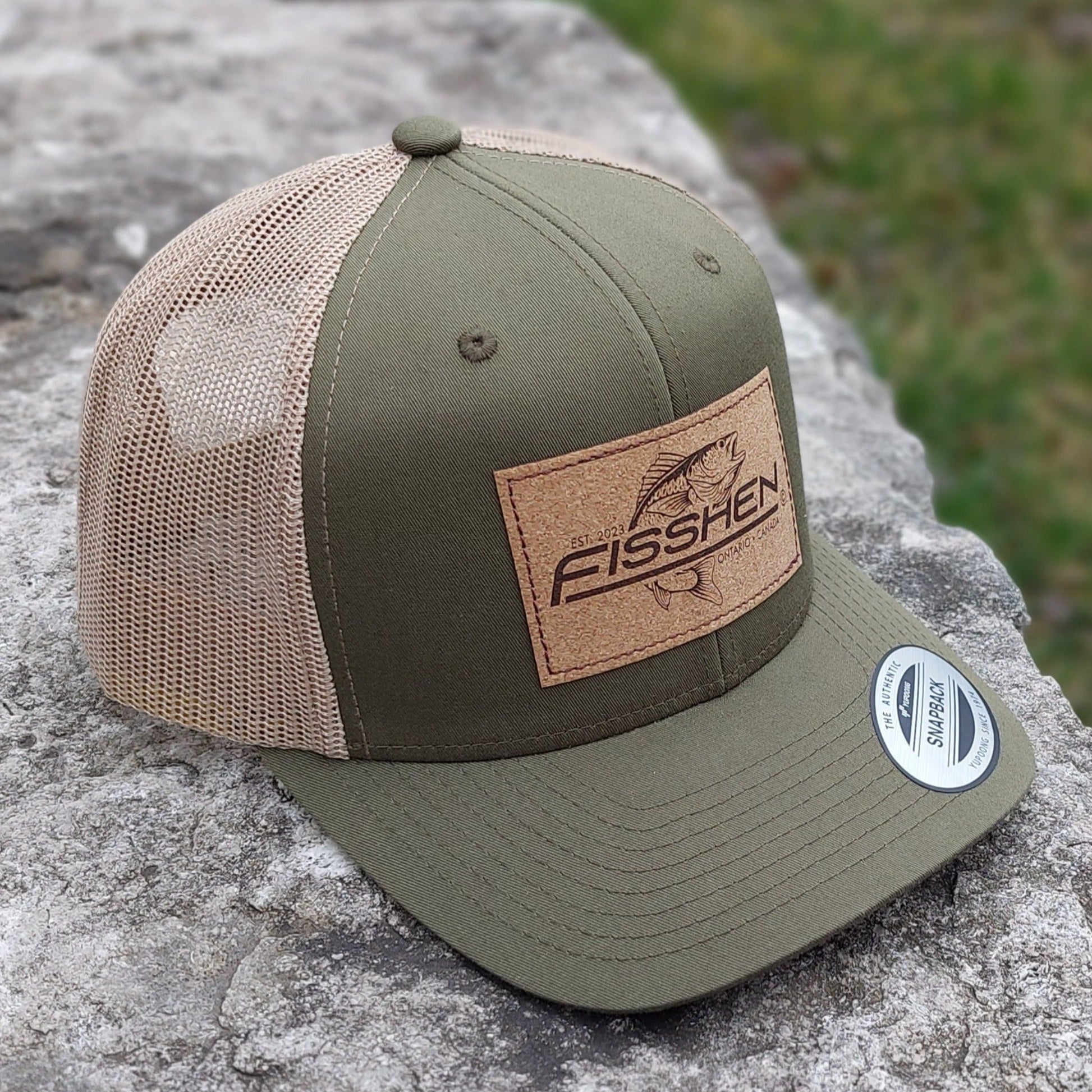Fishing design with the word Fisshen. Trout image on a cork patch. Hat is Moss green with taupe back